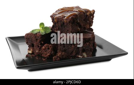 Köstliche Schokoladenbrownies mit Nüssen, Karamellsauce und frischer Minze auf weißem Hintergrund Stockfoto