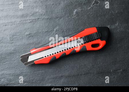 Cuttermesser auf schwarzem Tisch, Draufsicht. Bauwerkzeug Stockfoto