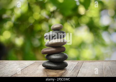 Gestapelte Steine auf Holztisch vor unscharfem Hintergrund. Zen-Konzept Stockfoto