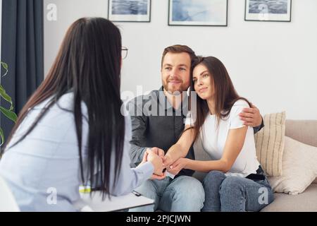 Das Paar sitzt auf dem Sofa und arbeitet mit einer Psychologin zusammen Stockfoto
