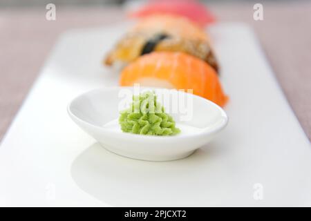 Schachtel Sushi und Brötchen mit Stäbchen, Ingwer, Wassabi und Sojasoße. Lebensmittellieferung an das Haus während des Coronavirus, Lebensmittel in Kartons, Beuteln und Einweg-Lebensmittelbehälter. Bleib drinnen. Hohe Qualität Stockfoto