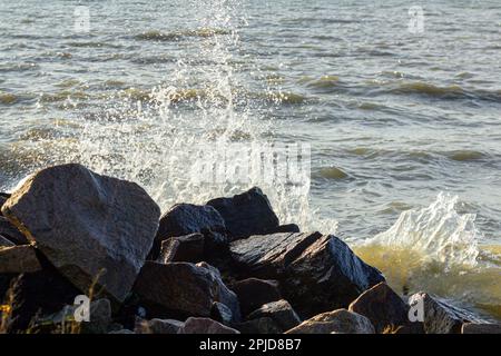 Eine wunderschöne Küste mit einer Welle und großen Steinen, die Wellen brechen auf den Felsen Stockfoto