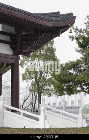 Ein vertikales Bild von einem japanischen Tempeldach und Säulen, umgeben von üppig grünen Bäumen Stockfoto