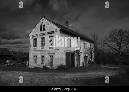 Verfallenes, altes Bauernhaus im Mostviertel Niederösterreichs in düsteren und düsteren Schwarz-Weiß Stockfoto