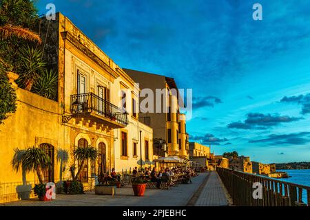 Sonnenuntergang über den Häusern entlang der Küste von Alfeo in Ortigia, dem ältesten Teil der Stadt Syrakus. Syrakus, Sizilien, Italien, Europa Stockfoto