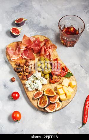 Antipasto-Platte mit Schinken, Prosciutto, Blauschimmelkäse, getrockneten Tomaten, Feigen und Oliven auf einem Holzbalken. Stockfoto