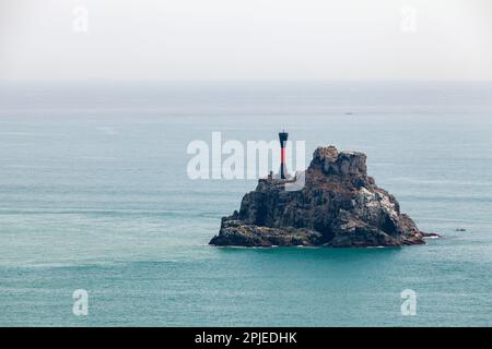 Markierung Für Isolierte Gefahr. Der schwarze Leuchtturm mit rotem Streifen befindet sich auf einer kleinen felsigen Insel im Meer von Japan in der Nähe von Busan, Südkorea Stockfoto