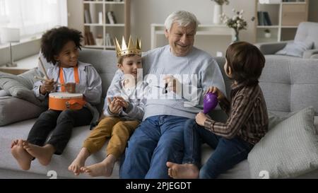 Glücklicher Enkel und multiethnische Freunde, die mit positivem Opa spielen Stockfoto