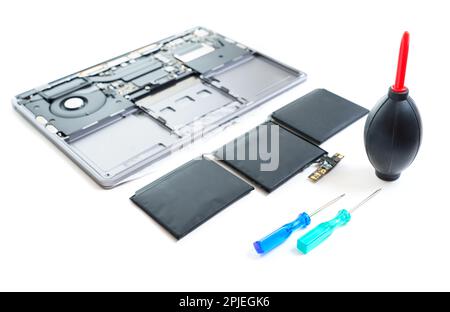 Geschwollener Laptop-Akku neben einem demontierten Laptop, Schraubendreher und ein Luftgebläse zum Entfernen von Staub von den Komponenten. Essentials Stockfoto