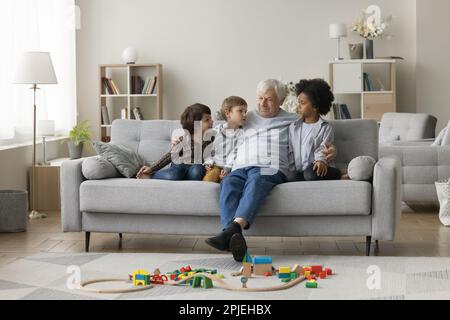 Süße, vielfältige kleine Enkel, die den alten Großvater besuchen Stockfoto