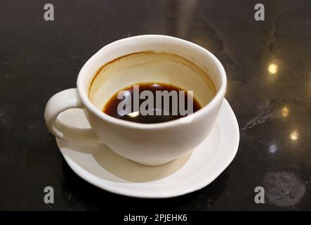 Halbe Tasse heißer Kaffee isoliert auf schwarzem Tisch Stockfoto