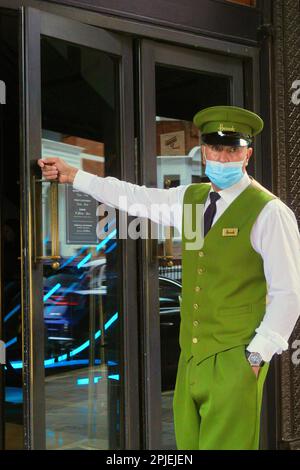 London, England, 20. August 2021: Berühmter Portier von Harrod mit Gesichtsmaske und unverwechselbarer leuchtend grüner, goldgeknöpfter Uniform. Stockfoto