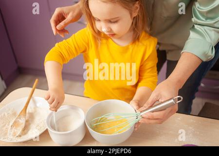 Großmutter und Enkelin bereiten Kuchenteig zu, verbringen Zeit miteinander, Familienbeziehungen, Liebe. Gewinnt Zucker Stockfoto