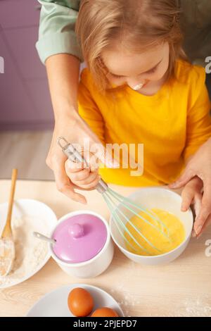 Großmutter und Enkelin bereiten Kuchenteig zu, verbringen Zeit miteinander, Familienbeziehungen, Liebe. Schlagen Sie Teig ein Stockfoto