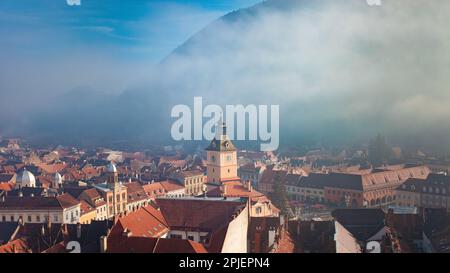 Blick auf Brasov, Rumänien, Berge und Nebel, wunderschönes historisches Zentrum mit orangefarbenen Häusern. Stockfoto