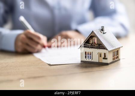 Person, die einen Hausvertrag über Versicherung, Hypothek, Verkauf oder Kauf unterzeichnet. Stockfoto