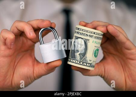 Ein Geschäftsmann mit einem silbernen Vorhängeschloss und einem Bündel Dollar in der Hand. Geldsicherheit. Stockfoto