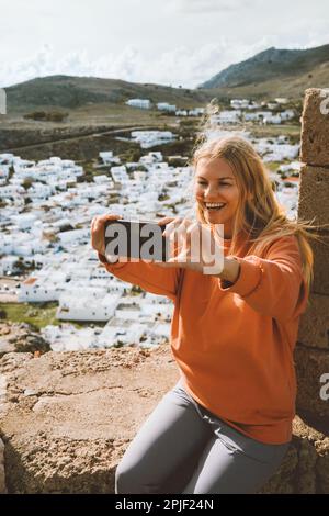 Reise-Bloggerin Frau macht Selfie-Foto von Smartphone-Kamera-Influencer-Mädchen in Griechenland und besichtigt Lindos Stadt aus der Vogelperspektive Rhodos Insel Sommerurlaub Stockfoto