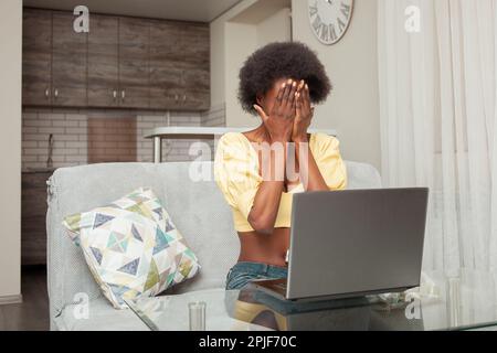 Porträt einer afroamerikanischen Schwarzen zu Hause. Drinnen ist die Frau verängstigt, schockiert, unangenehm überrascht, wütend. Emotionen, die vor mir sitzen Stockfoto