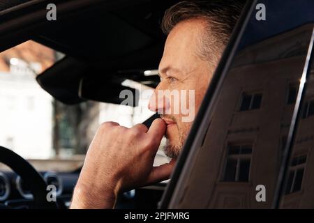 Attraktiver Geschäftsmann in einem lässigen Stoff, der ein Auto in der Stadt fährt, Probefahrt Stockfoto