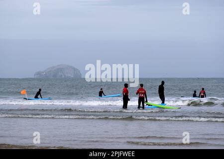 Dunbar, Schottland, Großbritannien. 2. April 2023 Menschen, die das sonnige, aber trügerisch kalte Wetter entlang der östlichen Lothian Küste in Belhaven Bay genießen. Temperatur um 5C Grad in der Brise. Blick über die vierte Mündung in Richtung Bass Rock. Surfen auf den Wellen. Kredit: Craig Brown/Alamy Live News Stockfoto