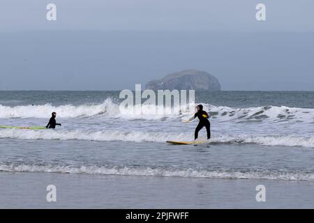 Dunbar, Schottland, Großbritannien. 2. April 2023 Menschen, die das sonnige, aber trügerisch kalte Wetter entlang der östlichen Lothian Küste in Belhaven Bay genießen. Temperatur um 5C Grad in der Brise. Blick über die vierte Mündung in Richtung Bass Rock. Surfen auf den Wellen. Kredit: Craig Brown/Alamy Live News Stockfoto