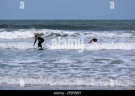 Dunbar, Schottland, Großbritannien. 2. April 2023 Menschen, die das sonnige, aber trügerisch kalte Wetter entlang der östlichen Lothian Küste in Belhaven Bay genießen. Temperatur um 5C Grad in der Brise. Surfen auf den Wellen. Kredit: Craig Brown/Alamy Live News Stockfoto