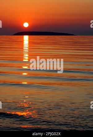 Sonnenuntergang über Puffin Island von Penmaenmawr Beach, North Wales. Stockfoto