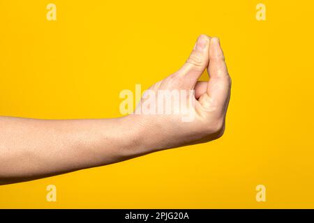 Nahaufnahme der Hand eines kräftigen Mannes, der die italienische Geste des ma que cosa Gesichts macht, isoliert auf gelbem Hintergrund. Stockfoto