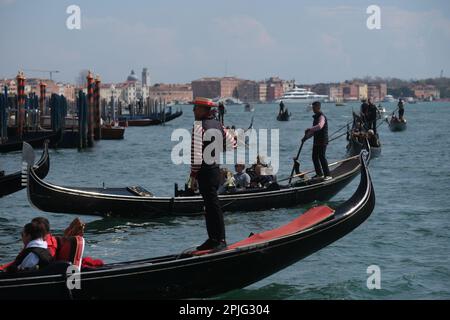 Gondoliere rudern ihre Gondeln mit Touristen an Bord entlang der Kanäle von Venedig, Italien, 2. April 2023 Stockfoto