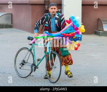 Minsk, Belarus - 13. Juni 2015: Ballonverkäufer in extravaganten Kostümen mit Fahrrad. Trauriges Gesicht Stockfoto