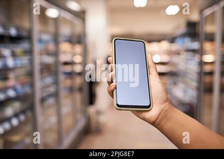 Nahaufnahme eines weiblichen Smartphones mit weißer Bildschirmdarstellung im Innenraum eines Supermarkts Stockfoto