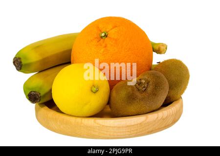 Obst, Bananen, Orange, Zitrone und Kiwi liegen auf einer Holzschüssel isoliert auf weißem Hintergrund. Stockfoto