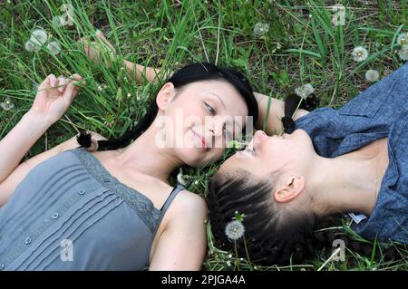 Zwei junge, schöne Frauen in stiller Kommunikation auf der Frühlingswiese Stockfoto
