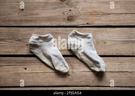 Schmutzige kurze weiße Socken liegen auf dem Holzboden des Hauses aus nächster Nähe Stockfoto