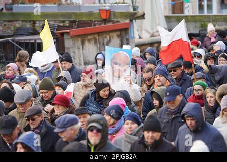 Danzig, Polen, April 2. 2023 mehrere hundert Menschen mit Porträts von Johannes Paul II. Und Flaggen des Vatikans gingen in das sogenannte. Papstmarsch zur Verteidigung von Papst Johannes Paul II. Am 2. April 2023 in Danzig, Polen. Die Teilnehmer des marsches sind hauptsächlich Rentner und ältere Menschen, inspiriert von katholischen Priestern und Politikern der herrschenden rechtsgerichteten Koalition. Der marsch wurde nach einem hochrangigen TVN-Bericht organisiert, der enthüllte, dass der Papst über Pädophilie in der katholischen Kirche Bescheid wusste und aktiv dazu beitrug, sie zu verbergen, einschließlich der Überstellung von Priestern, die der Pädophilie verdächtigt werden, in andere Gemeinden. Cre Stockfoto