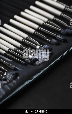Ein Satz Ölbürsten und Palettenmesser, isoliert auf schwarzem Hintergrund, Nahaufnahme Stockfoto