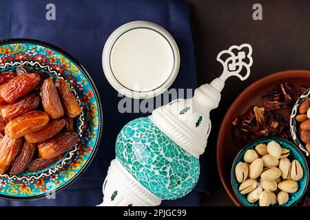Ramadan Kareem – Speisen und Getränke. Datteln Sie Früchte, Nüsse und Milch auf dunklem Hintergrund. Das Ramadan-Karäm-Fasting-Monatskonzept. Draufsicht Stockfoto