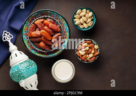 Ramadan Kareem – Speisen und Getränke. Datteln Sie Früchte, Nüsse und Milch auf dunklem Hintergrund. Das Ramadan-Karäm-Fasting-Monatskonzept. Draufsicht Stockfoto