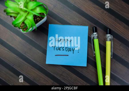 Konzept des Happy Tuesday Schreibens auf Haftnotizen isoliert auf Holztisch. Stockfoto