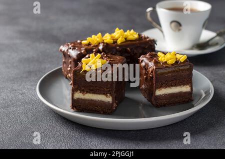 Schokoladen-Mandel-Brownie mit Mango und Passionsfruchtmarmelade überzogene Gourmet-Schokoladenglasur auf grauem Teller Stockfoto