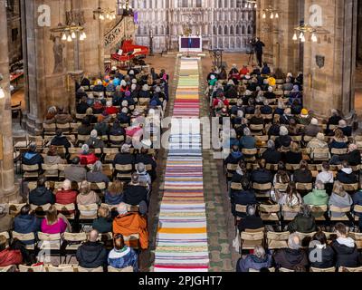 Marburg, Deutschland. 2. April 2023. St. Elisabethkirche in Marburg, wichtige mittelalterliche Wallfahrtskirche: Ein farbenfroher, 48 Meter langer, gewebter Passionsteppich wurde während des Gottesdienstes in der palmensonntagskirche entrollt, handgefertigt von Gemeindemitgliedern und Besuchern über einen Zeitraum von sechs Wochen mit einem alten Webstuhl. Der protestantische liturgische Dienst wurde von den Pastoren Achim Ludwig (in der Kanzel) und Matti Fischer geleitet. Kredit: Christian Lademann / Lademannmedia Stockfoto