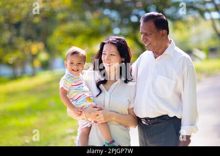 Familienspaziergängen im Sommerpark. Eltern und Kinder im Freien. Mutter, Vater und Kinder spielen, lachen, picknicken im sonnigen Garten. Stockfoto