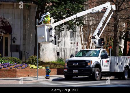 Ein Arbeiter in einem Versalift LKW, Hubarbeitsbühne, installiert ein Einbahnschild in Washington DC. Stockfoto