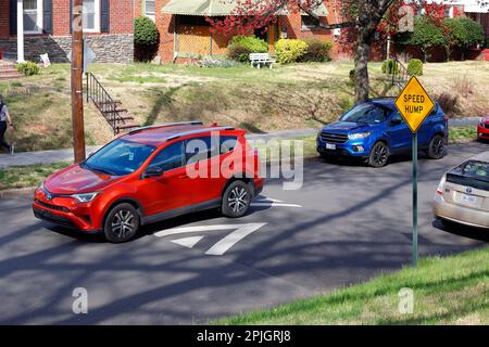 Ein rotes Auto fährt über eine Geschwindigkeitserhöhung, Geschwindigkeitsbuckel. Speed Buckps wurden entwickelt, um die Verkehrsgeschwindigkeit auf Straßen mit geringer Verkehrsdichte zu verringern, insbesondere in Wohngebieten Stockfoto