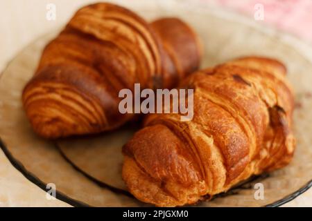 Frische, goldene Blättercroissants zum Frühstück in der Nähe auf einem Teller Stockfoto