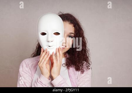 Lächelnden jungen Frau spähen hinter der Maske Stockfoto