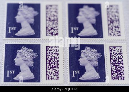 Ein offenes Buch mit selbstklebenden, indigo farbigen, erstklassigen Stempeln mit Queen Elizabeth II- und QR-Codes. März 2023, Großbritannien. Stockfoto