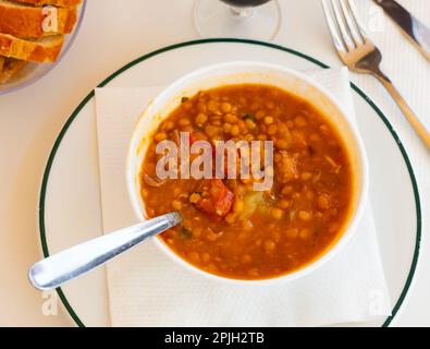 Auf dem Tisch wird ein spanischer Linseneintopf serviert Stockfoto