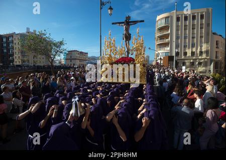 Eine allgemeine Ansicht zeigt die Ritter der „Salud“-Bruderschaft, die einen Thron mit einer Statue Christi trägt, während sie an der Prozession während der Feierlichkeiten der Heiligen Woche teilnehmen. Tausende von Menschen feiern die Heilige Woche und warten darauf, die Bruderschaften und Osterprozessionen auf den Straßen der Stadt zu sehen. Die Heilige Woche in Andalusien, die Tausende von Gläubigen und Gläubigen zusammenbringt, gilt als eine der wichtigsten religiösen und kulturellen Feierlichkeiten in der Region. Stockfoto